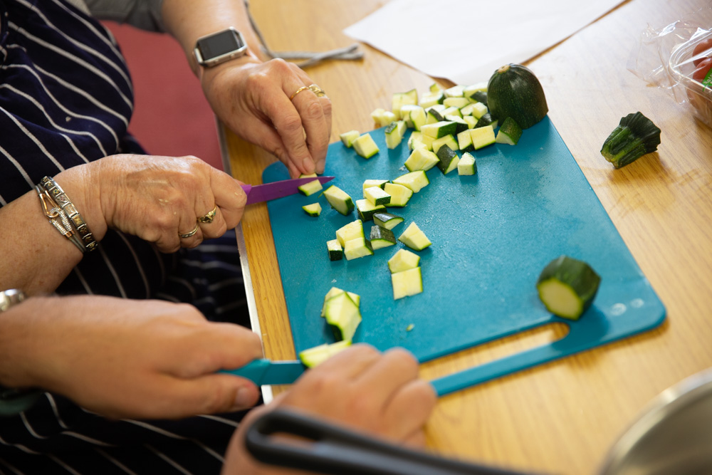 Two people cutting a courgette