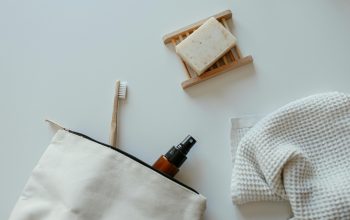 Toothbrush and glass bottle in a makeup bag. Bar of soap and towel to the right of the makeup bag.