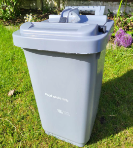 A 25 litre Food Waste bin for outside usage sat on a garden lawn